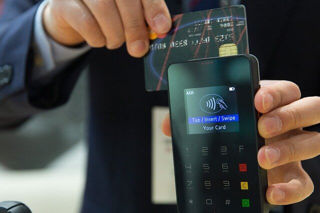 Negativação indevida - foto de um homem passando um cartão de crédito em uma máquina portátil.