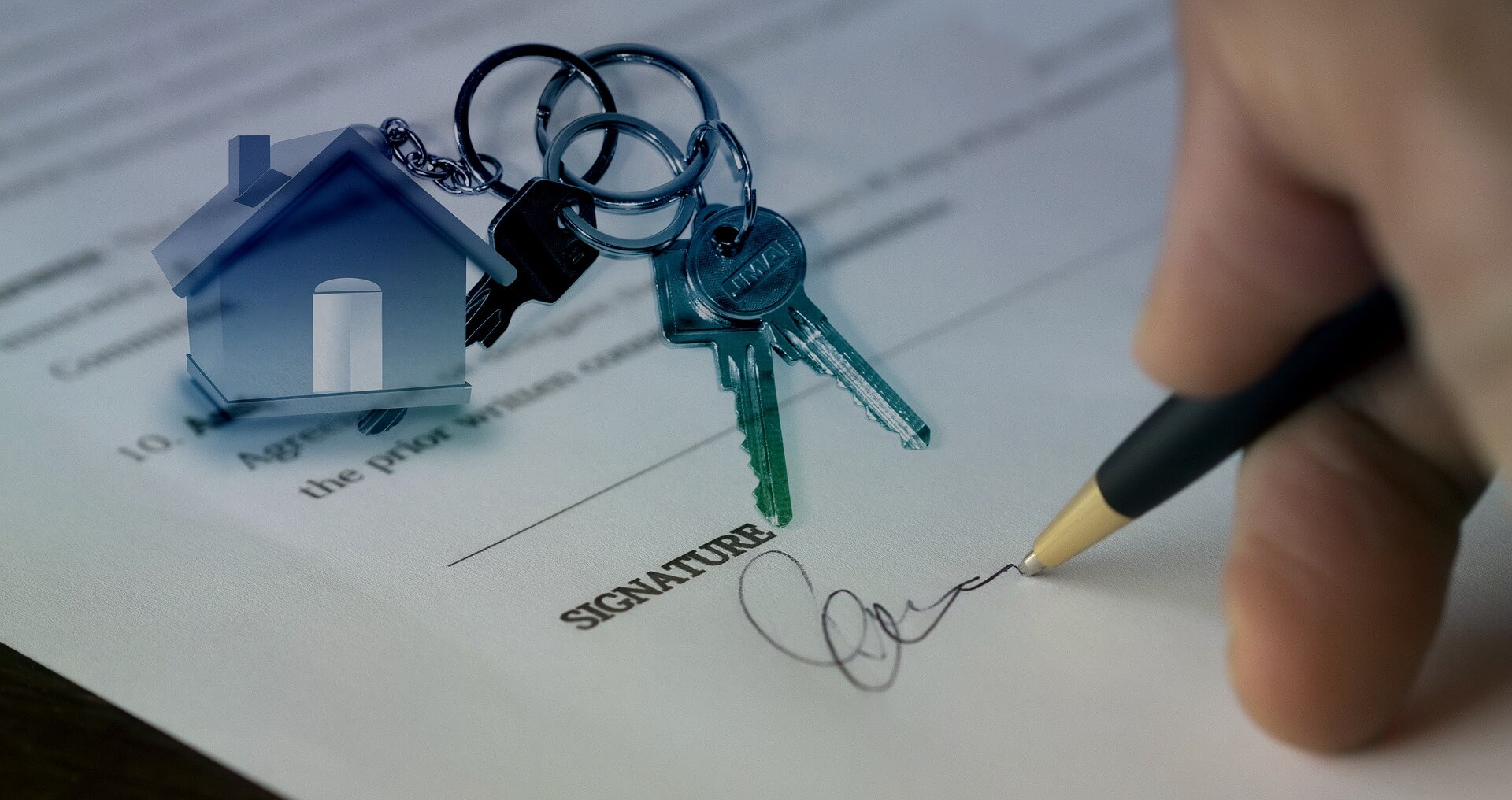Cuidados na compra de imóvel - foto de uma mão de uma pessoa branca, assinando um contrato. Por cima da foto, uma ilustração de uma casa e um molho de chaves