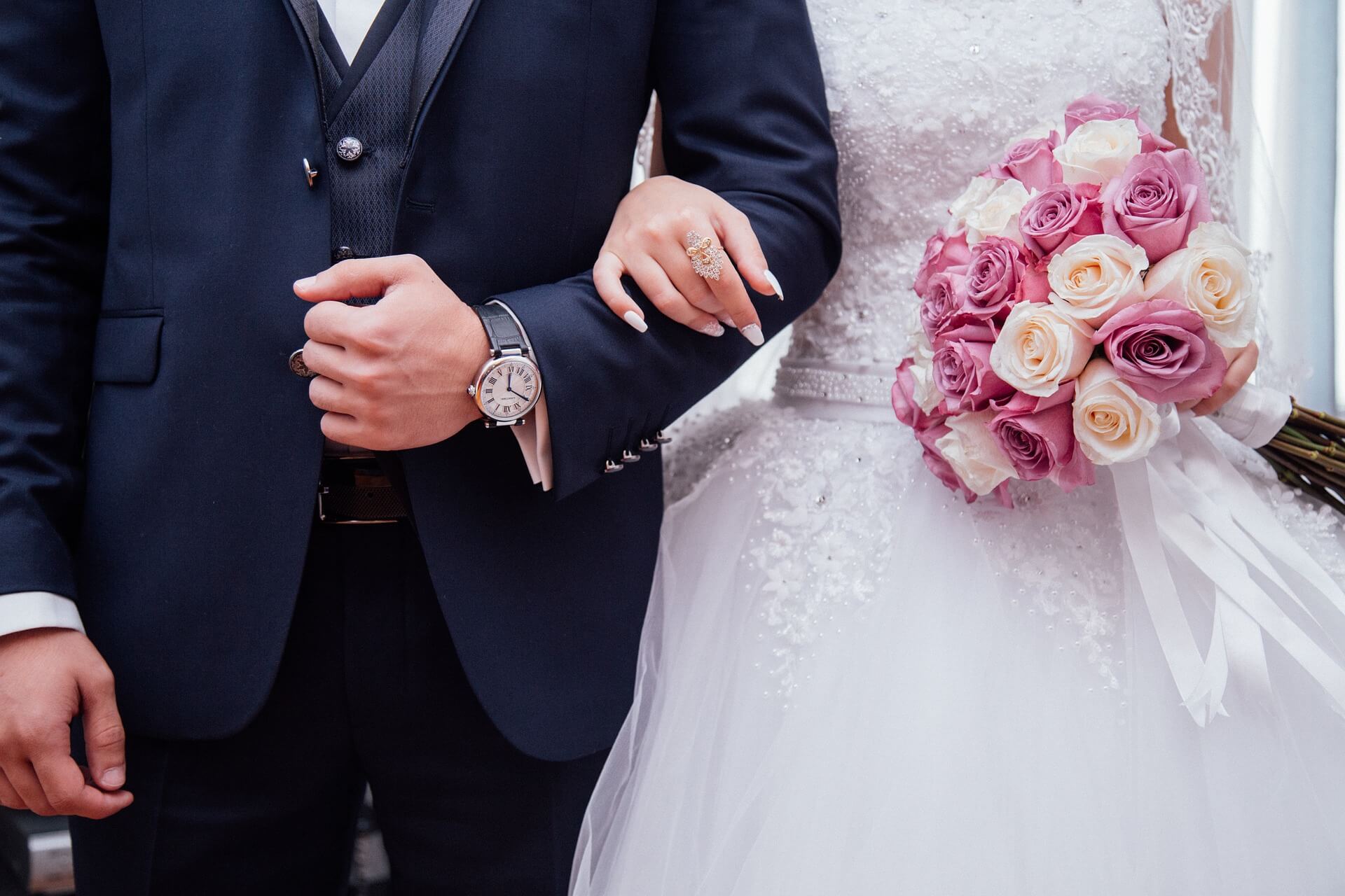 Pacto antenupcial 1 - imagem de um casal de noivos, com a noiva de branco, segurando um buquê de rosas e o noivo com terno azul-marinho