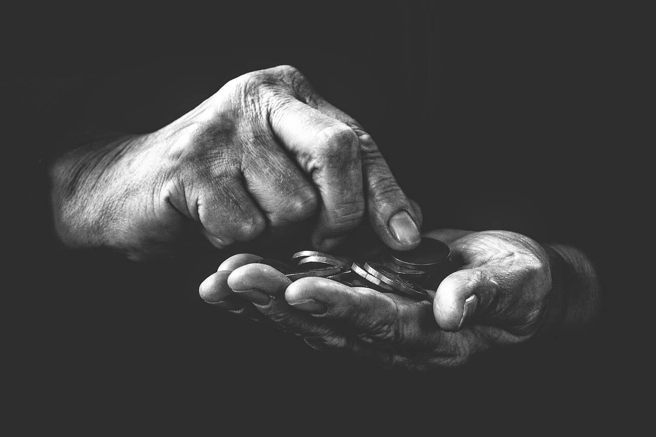 Inadimplência em condomínios - imagem em preto e branco de mãos de uma pessoa contando moedas